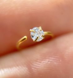 a person's hand holding a yellow gold ring with a white diamond in it