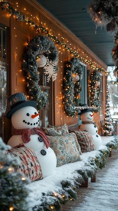 snowmen are lined up on the side of a building with wreaths and lights