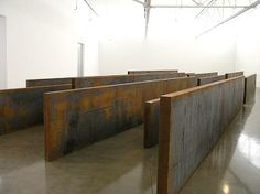 an empty room with metal dividers in the center and white walls behind it,