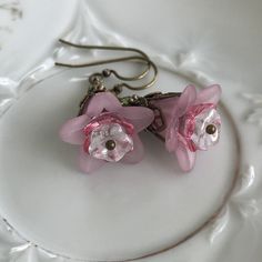 "Pretty in Pink... Add some spring to your wardrobe with these lovely double pink blossoms. Delicate pink petals surround bright pink and white centers. Antique brass filigree caps adorn the tops and a tiny green bead adds a bit of spring pop. These earrings are very lightweight and comfortable to wear. Perfect for a garden wedding, or a gift for a nature lover. And don't forget...Mother's Day is just around the corner. Drop length from bottom of antique brass french earwire: 1\" (25mm) Prefer a Feminine Flower-shaped Earrings For Gifts, Pink Earrings With Handmade Flowers For Spring, Pink Handmade Flower Earrings For Spring, Spring Pink Earrings With Handmade Flowers, Pink Petal-shaped Earrings For Spring, Rose Red Flower Earrings, Spring Pink Earrings With Flower Charm, Pink Flower Shaped Earrings For Spring, Pink Flower Shaped Jewelry For Spring