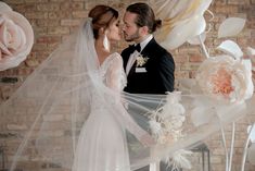 the bride and groom are kissing in front of paper flowers that look like they have been made out of feathers