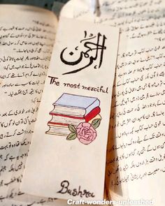 an open book with arabic writing on it and a rose in the middle is shown