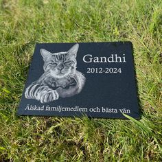 a black plaque with a cat on it sitting in the grass