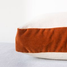 an orange and white pillow sitting on top of a bed