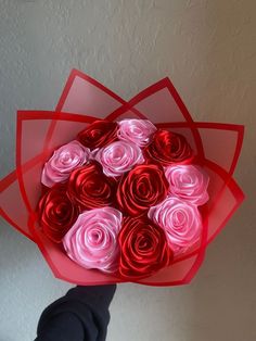 a person holding a bouquet of red and pink roses