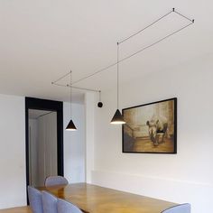 a dining room table with chairs and a painting on the wall above it in an apartment