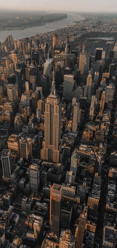 an aerial view of a city with skyscrapers and water in the background at sunset