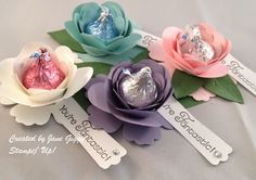 three paper flowers with candy wrappers in them