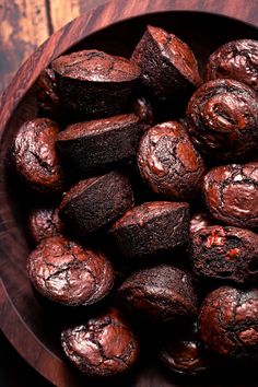 a wooden bowl filled with chocolate muffins on top of a table