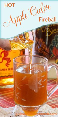 hot apple cider fireball is being poured into a glass mug