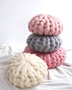 three different colored knitted balls sitting on top of each other in front of a white background