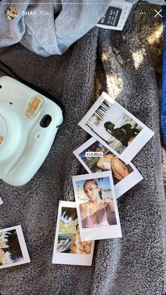 polaroid camera sitting on top of a blanket next to pictures and a cell phone