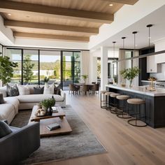 a living room filled with furniture next to a kitchen and dining room table on top of a hard wood floor