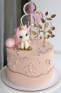 a pink cake with gold decorations and a little pony figurine sitting on top