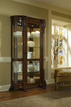 Museum-quality display options are at your fingertips with this well-scaled curved side curio in your home. The back of this tall curio cabinet sits flush against your wall to maximize visual impact without taking up too much floor space. The sides are curved maximizing the view of the mirror-backed interior. The single door opens from the front and is framed with ornate woodwork. Once the door is opened, it reveals five interior shelves to display your treasures. A handsome chocolate maple brow Corner Curio, Pulaski Furniture, Curio Cabinet, Nebraska Furniture Mart, Glass Shelves, Display Cabinet, Accent Furniture, China Cabinet, Wood Furniture