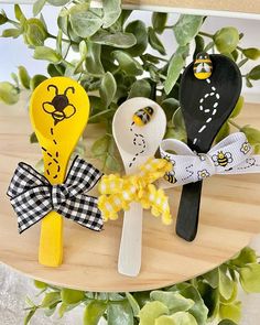 three wooden spoons with different designs on them sitting next to a potted plant