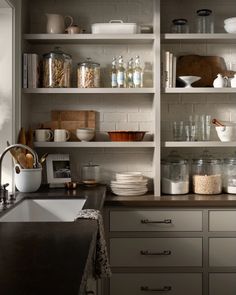 a kitchen filled with lots of open shelves and dishes on top of the counter tops