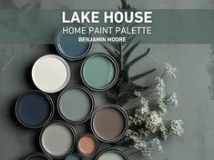 some paint cans are sitting next to a plant with white flowers in the background and text that says lake house home paint palette