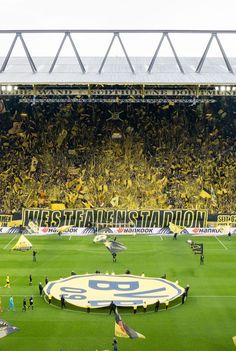 a stadium filled with lots of people standing on top of a soccer field next to a giant banner