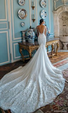 a woman in a wedding dress is standing near a table with plates and vases on it