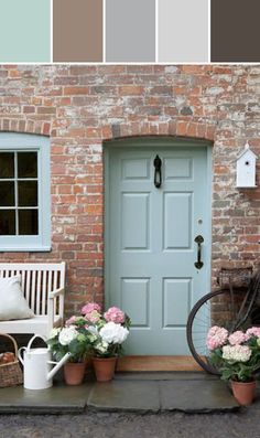 a bicycle parked next to a brick building with flowers in front of the door and two chairs