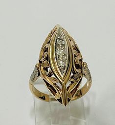 a gold ring with two diamonds on it's sides and a leaf design in the middle