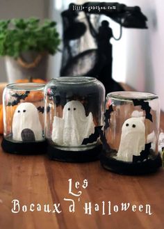 three glass jars with ghost decorations in them