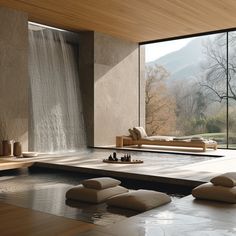 a room with a waterfall in the background and some pillows on the floor next to it