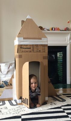 a little boy is sitting in a cardboard house