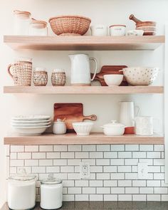 the shelves in the kitchen are filled with dishes and utensils, including wooden spoons