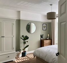 a bedroom with a bed, dresser and mirror on the wall next to each other