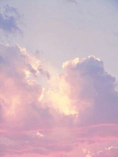 an airplane is flying in the sky at sunset or dawn with clouds and pink hues