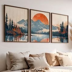 three paintings hanging on the wall above a couch in a room with pillows and blankets