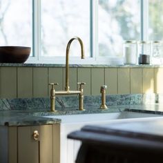 a kitchen with marble counter tops and brass faucets