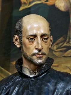 a close up of a statue of a man wearing a leather jacket and standing in front of a painting