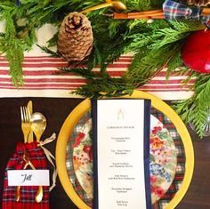 a place setting with pine cones, plaid napkins and goldware on the table