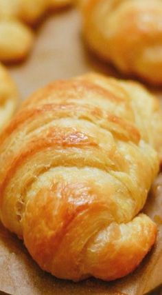 croissants and other pastries sitting on wax paper