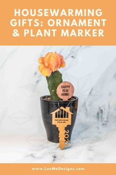 Cedar plant marker saying "happy new home!" in a moon cactus plant, with a cherry wood new home key ornament saying "our new home lisa & jim" on a marble background First Time Homebuyer, Happy New Home