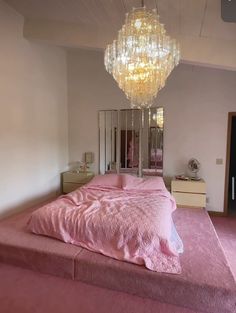 a bedroom with a pink bed and chandelier hanging from the ceiling