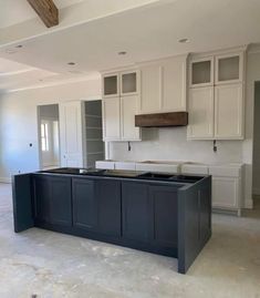 an empty kitchen with white cabinets and black counter tops in the middle of the room