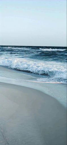 an empty beach with waves coming in to shore