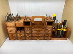 a wooden desk with many drawers and tools on it's sides, in front of a white backdrop