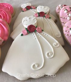 wedding dress decorated cookies with pink and white frosting on them are sitting next to each other