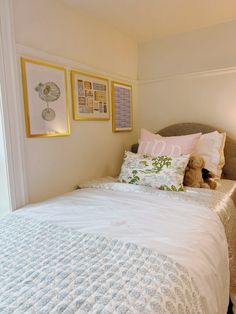 a white bed sitting next to two framed pictures on the side of a wall above it