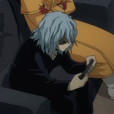 an anime character sitting on a couch holding a cell phone in his hand and looking at the screen