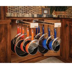 pots and pans are hanging on the wall in this kitchen cabinet with wooden cabinets