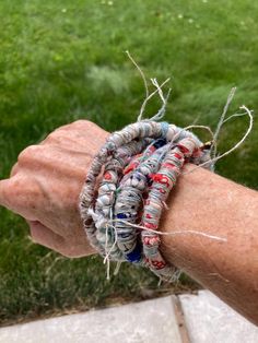 an older person's arm with several bracelets on it and grass in the background