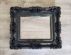 an ornate black frame on a wooden floor