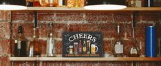 the shelves are filled with different types of liquors and beer glasses, including one that is labeled cheers