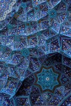 an intricately decorated wall in the middle of a building with blue and green tiles on it